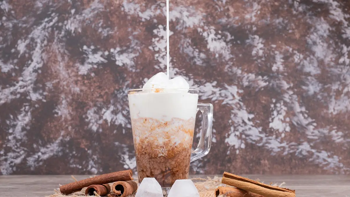 Glass with tasty drink and cinnamon on marble background