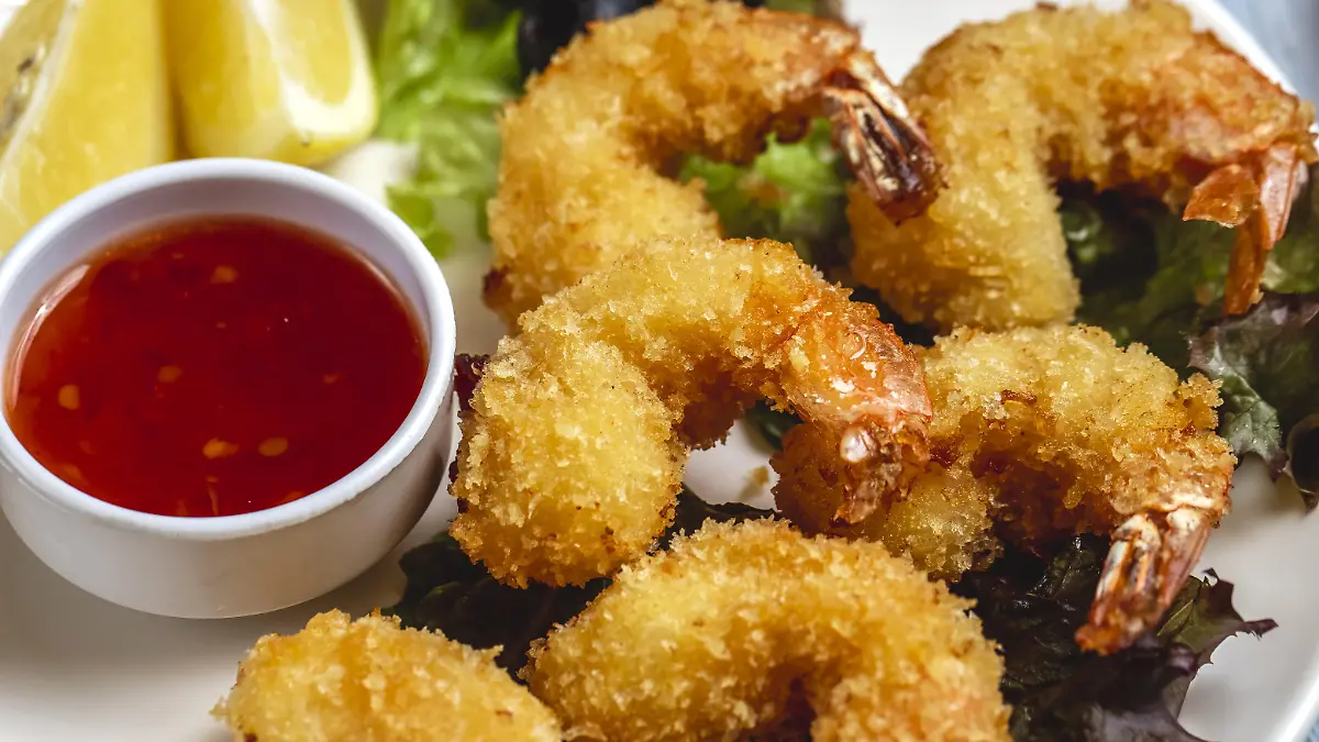 side view tempura shrimps with sweet chili sauce slice of lemon and black olive on a plate