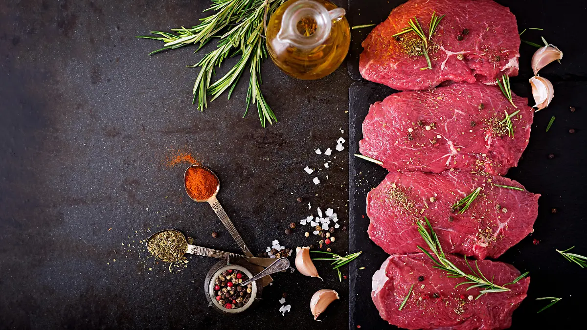 Raw beef steaks with spices and rosemary. Flat lay.Top view
