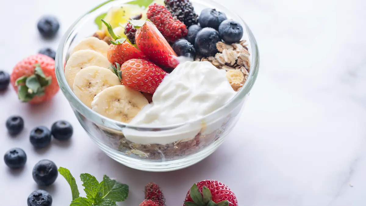 bowl of oat granola with yogurt, fresh blueberries, mulberry, st