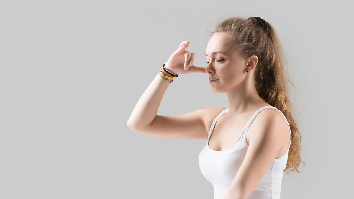 Young attractive woman making Alternate Nostril Breathing, grey