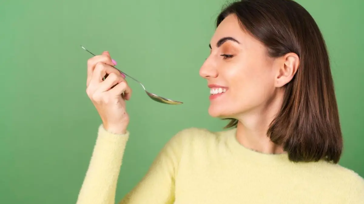 mujer joven verde sueter amarillo apetito come cucharada disfrutando