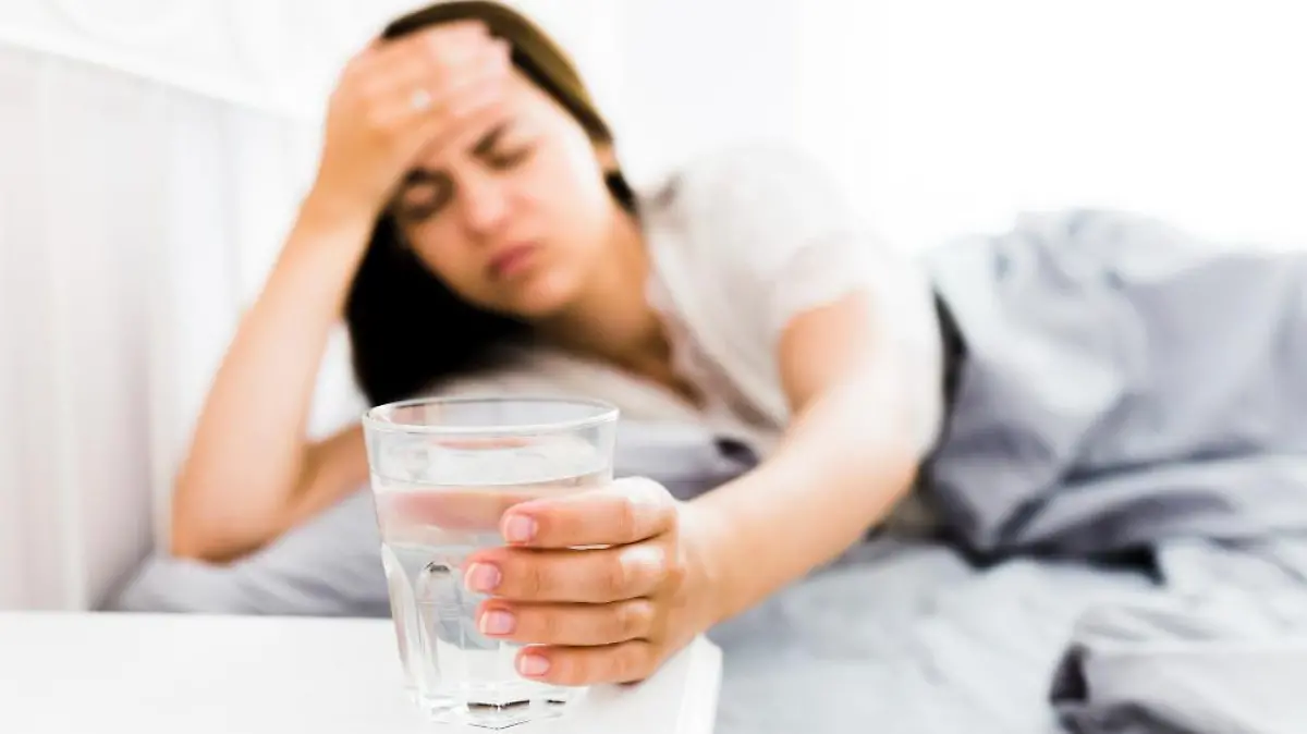mujer dolor cabeza tomando vaso agua