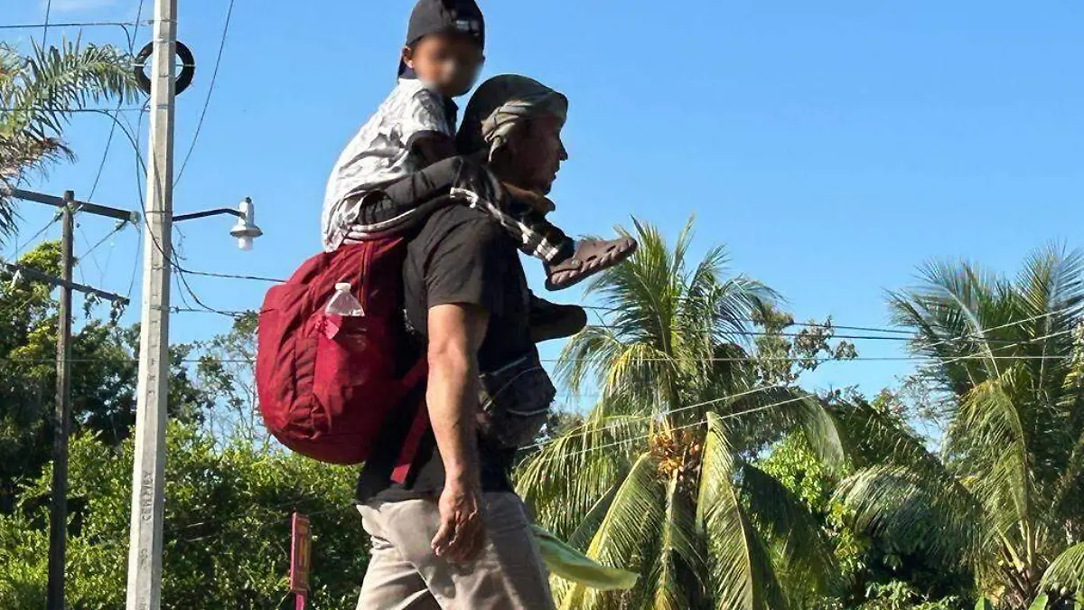 niño migrantes en hombros de su padre