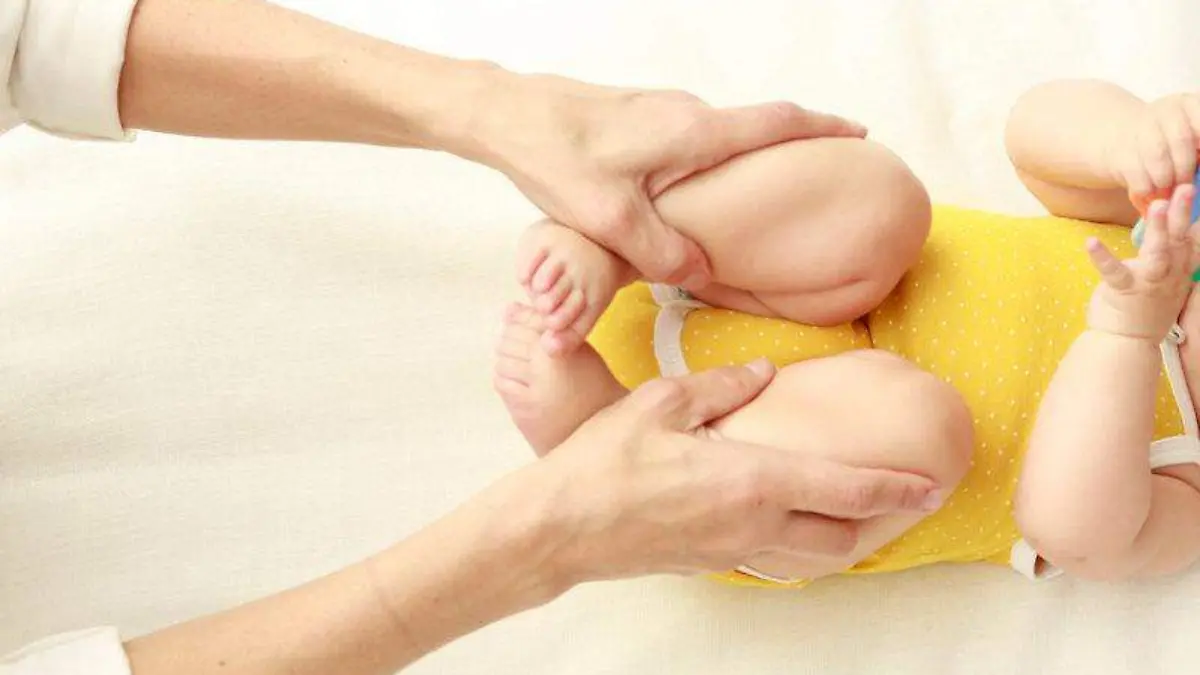 3. Con el bebé boca arriba, coge con tus manos sus piernas, dóblalas por las rodillas y llévalas hacia su estomago, presionándolo ligeramente. Vuelve a extenderlas y repite varias veces.