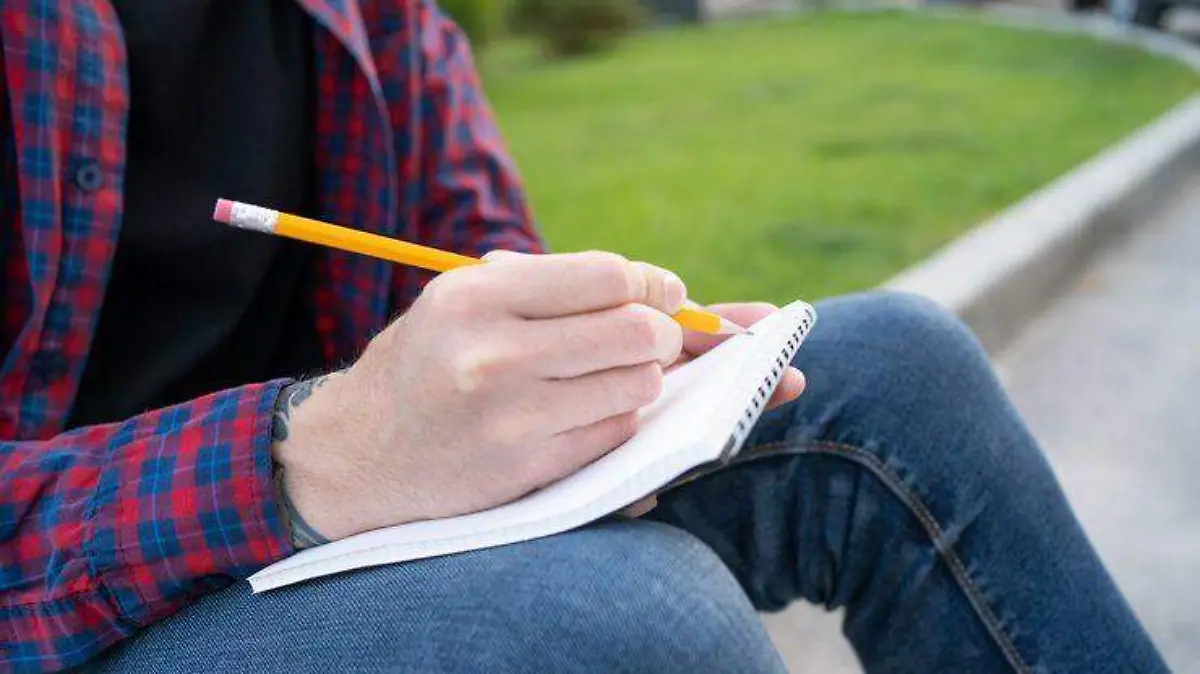 hombre-irreconocible-sentado-acera-camino-escribiendo-nota_74855-6100