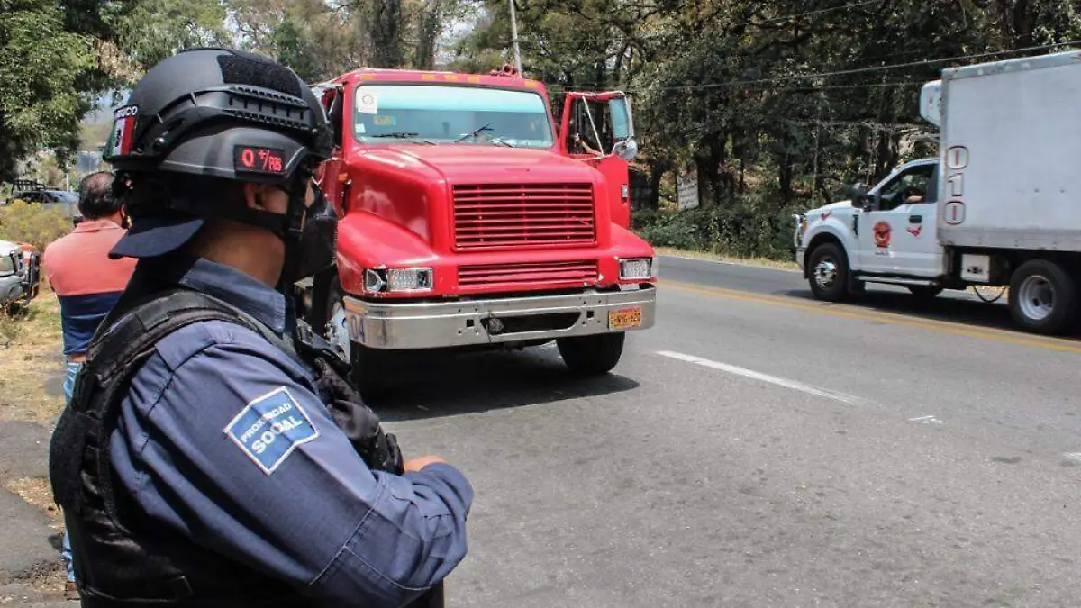 Un policía de Cuernavaca en punto de revisión de vehículos pesados en El Capote y al fondo un camión rojo