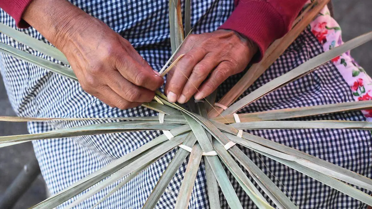 Ahí, sobre la banqueta, al paso de los vehículos no se distrae, concentrada mueve las manos de manera diestra.