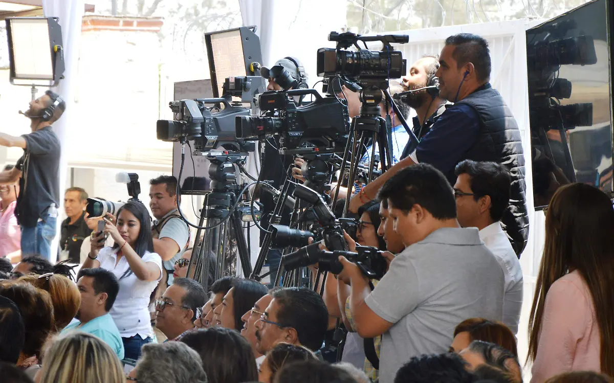 Reporteros gráficos realizan sus labores en una tarima