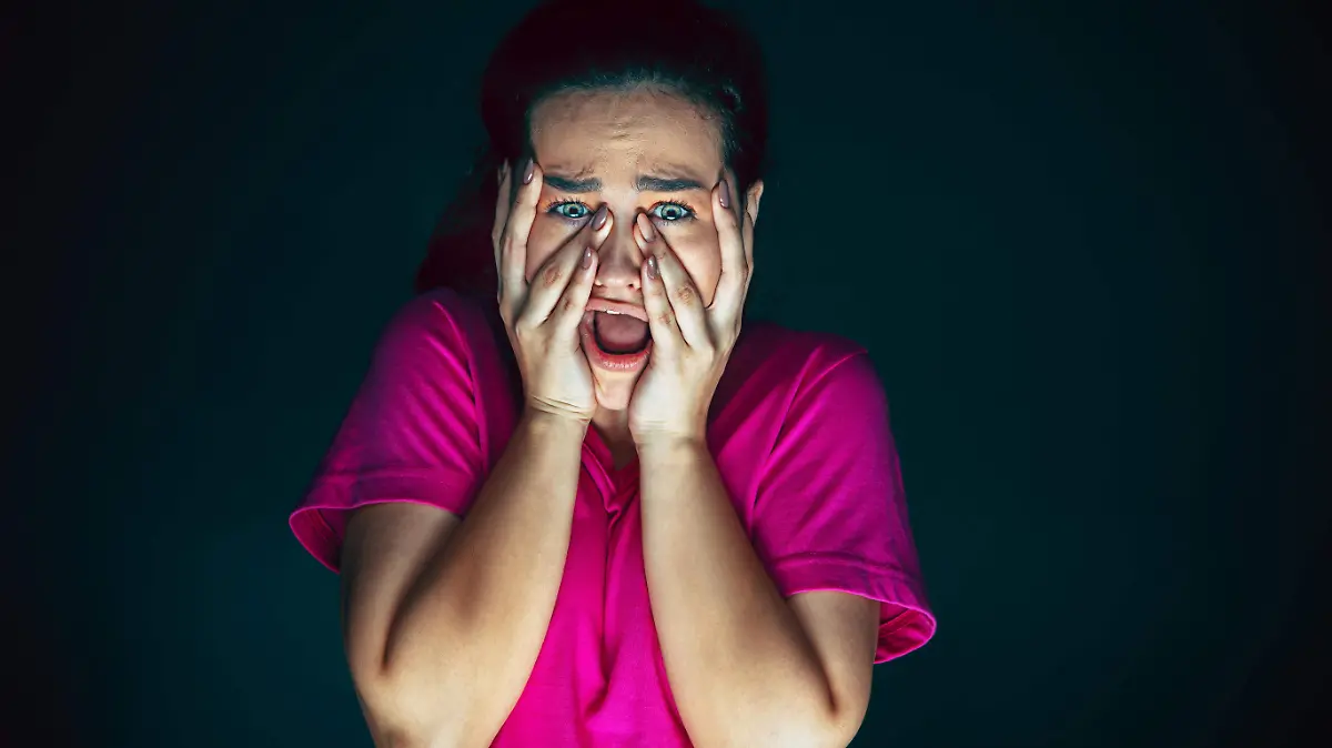 close-up-portrait-of-young-crazy-scared-and-shocked-woman-isolated-on-dark