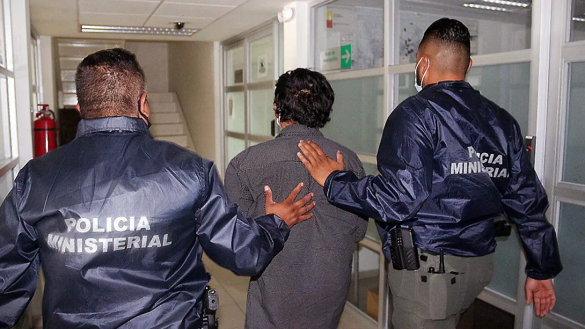 Policías ministeriales caminan con persona detenida