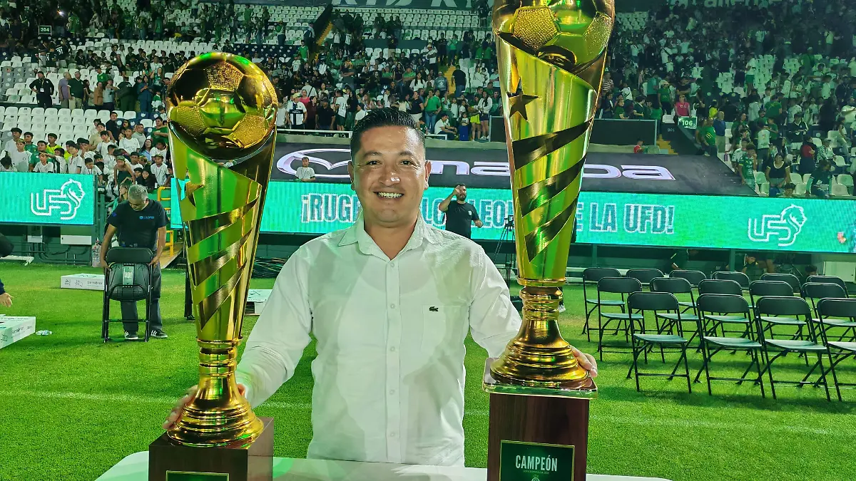 Joaquín Aguilar posa con los trofeos a entregarse al equipo campeón y subcampeón
