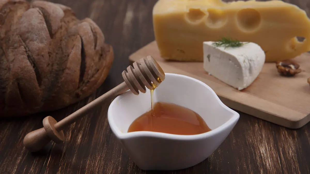 front-view-honey-saucer-with-variety-cheeses-stand-with-walnuts-loaf-bread-wooden-background (1)