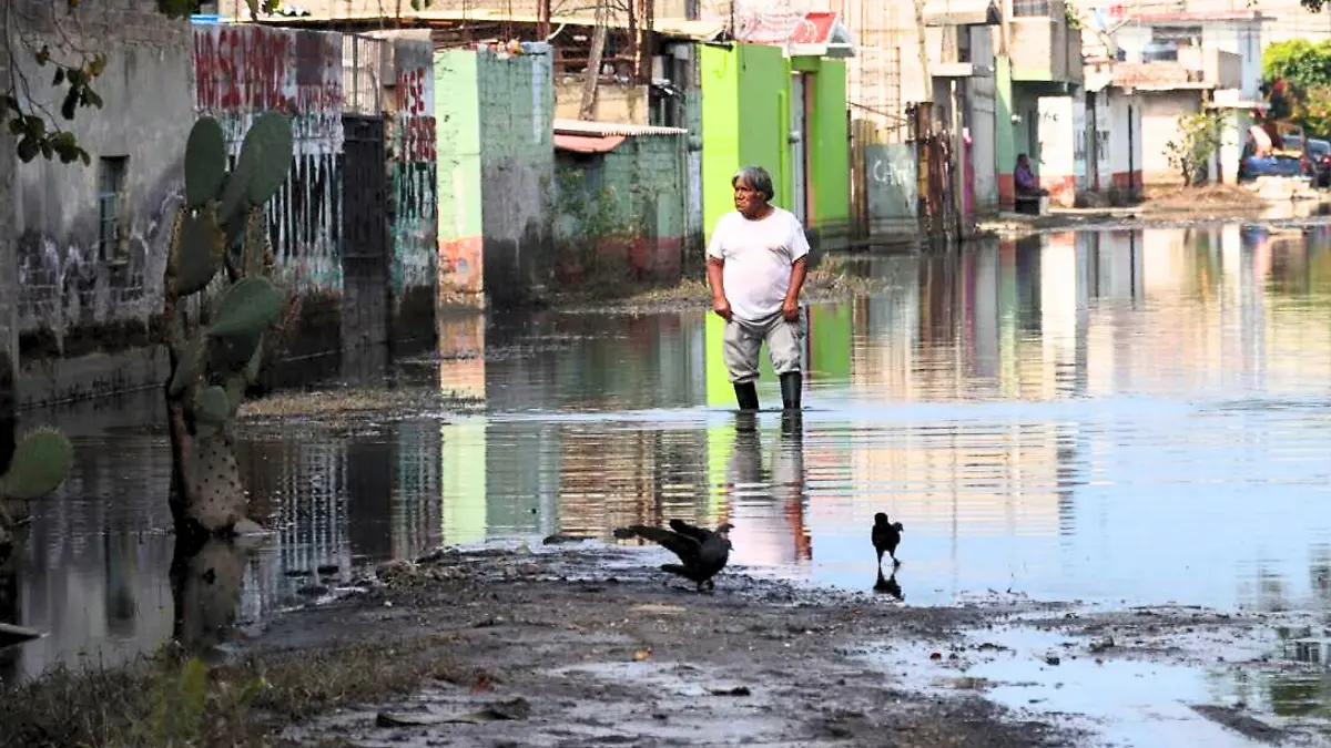 habitante de chalco con botas de goma camina entre aguas anegadas