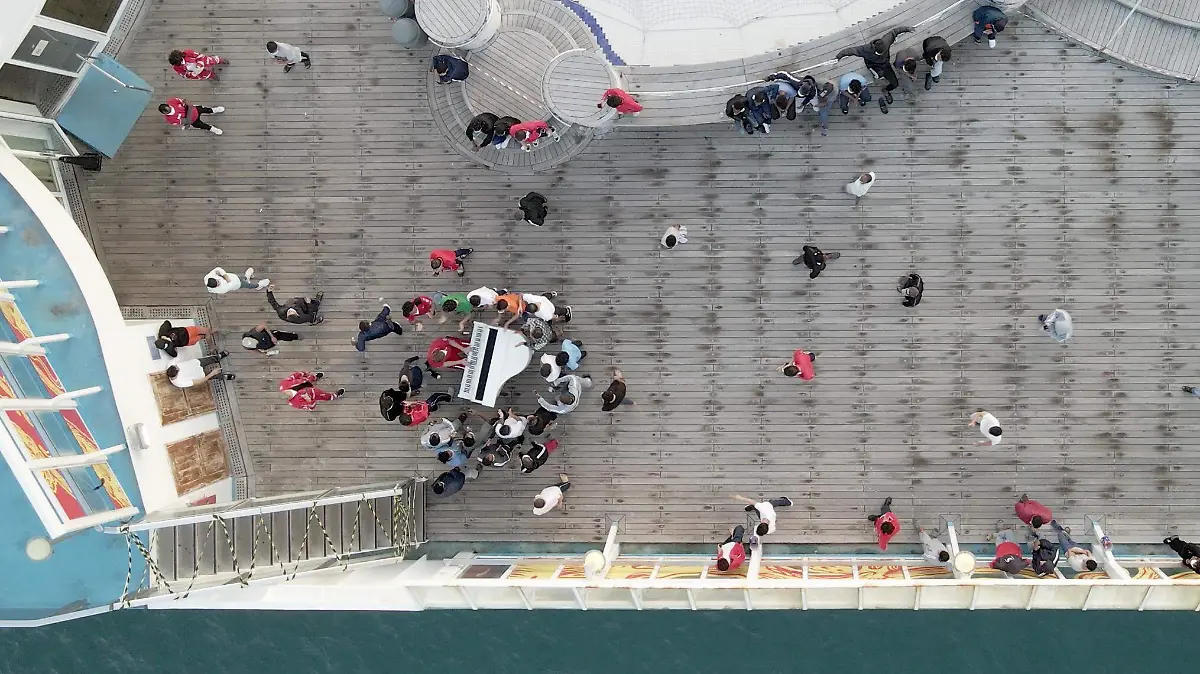 A drone shot of migrants listening to the piano on deck