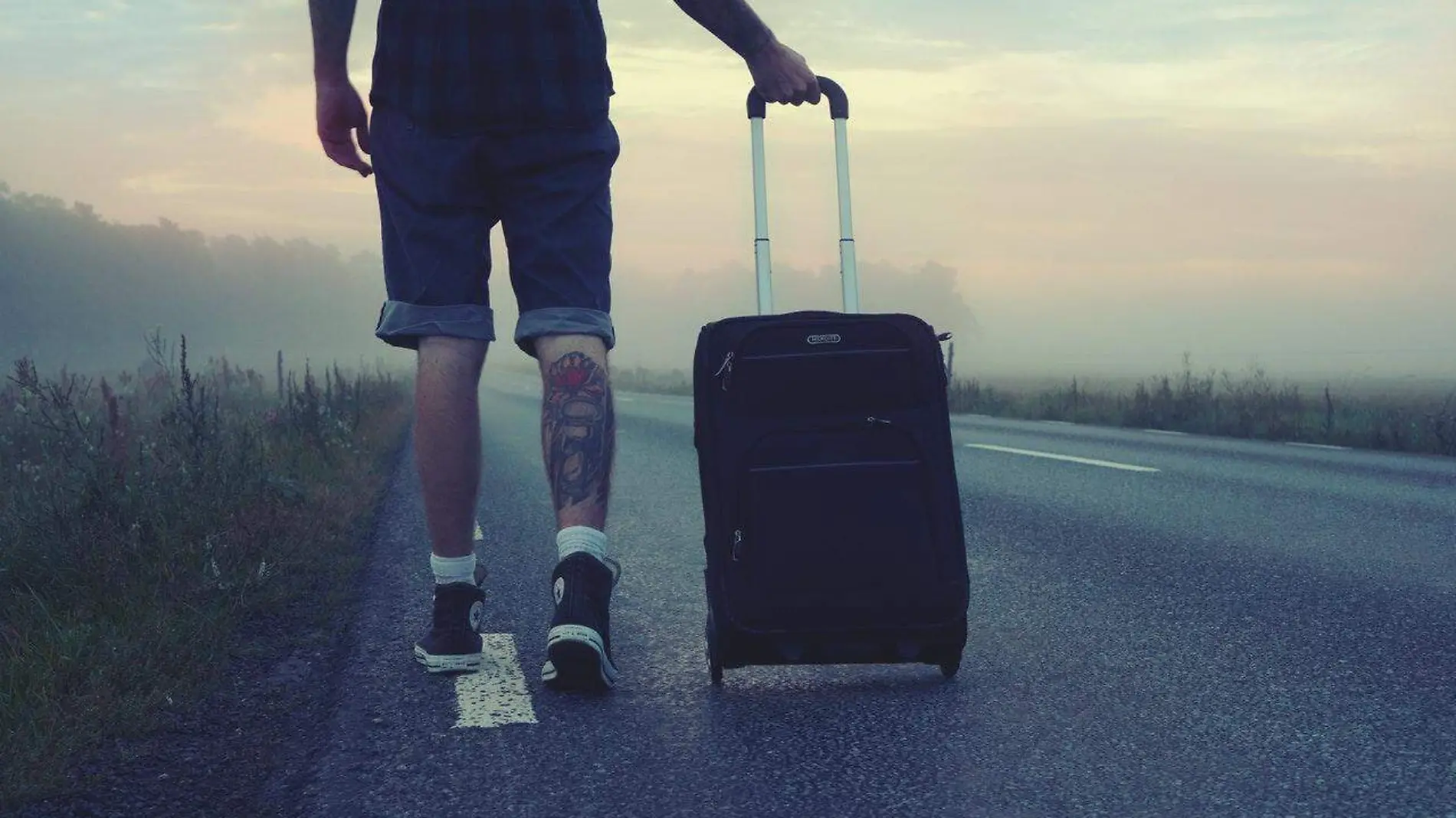 man-walking-on-the-road-holding-black-luggage-during-sunset-160483