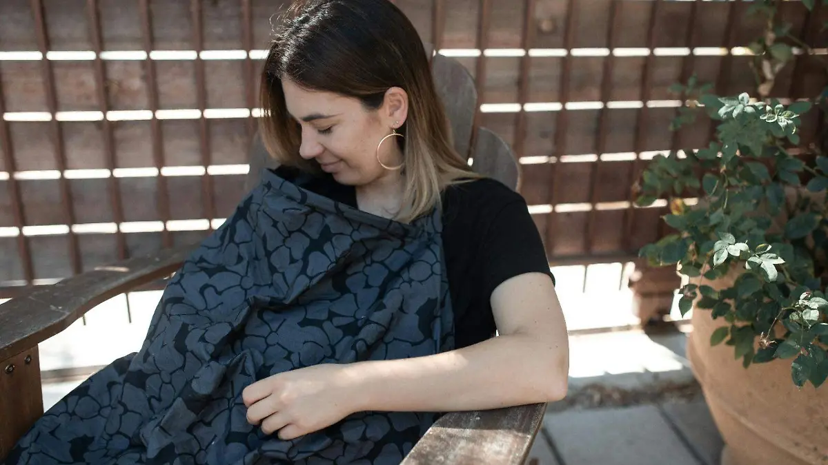 Mujer amamantando y cubriendose con una manta