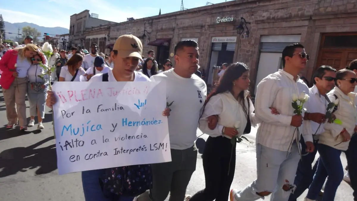 Persona con cartel pidiendo justicia por la familia Mujíca Hernández