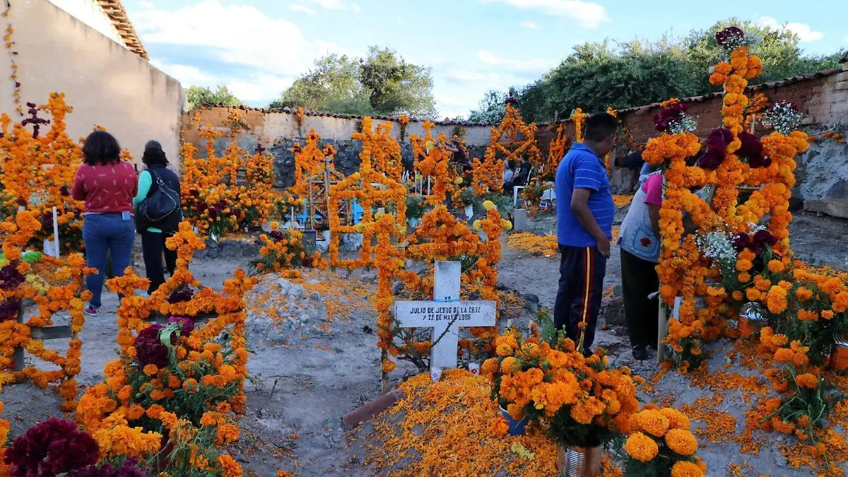 Personas adornando tumbas de familiares en el panteón de Janitzio