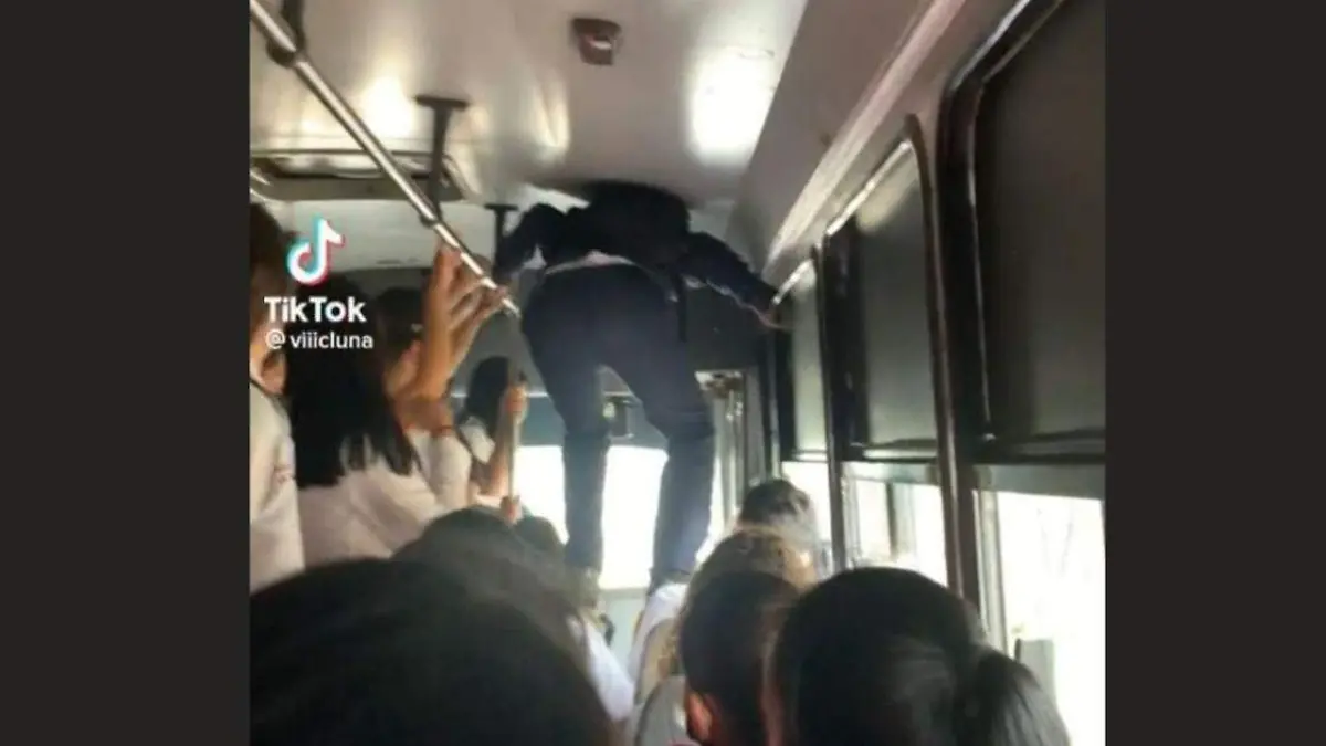 Joven camina sobre asientos para descender de autobús lleno