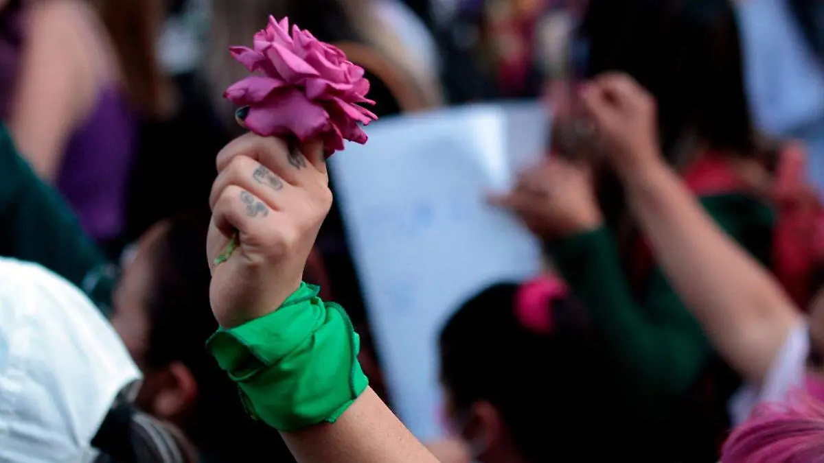 mano sostiene flor de color morado durante una marcha del 8M