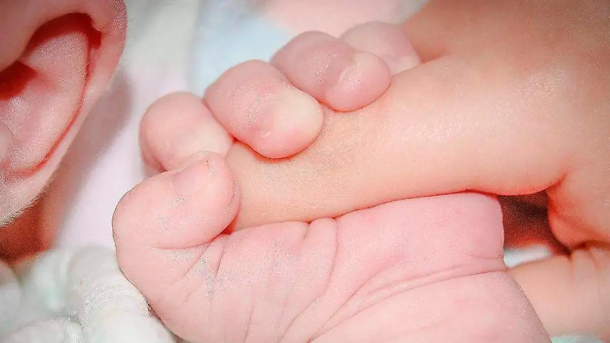 bebé recien nacido sostiene el dedo de una mujer con su mano