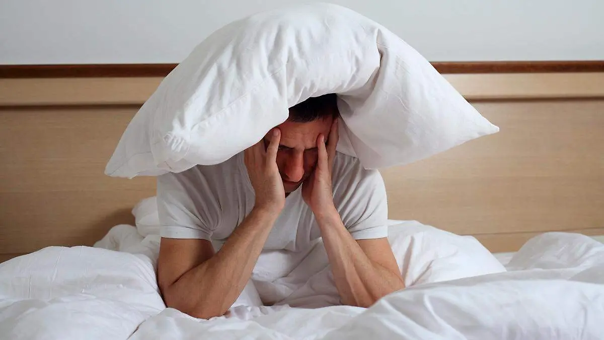 persona con problema de sueño con una almohada en su cabeza