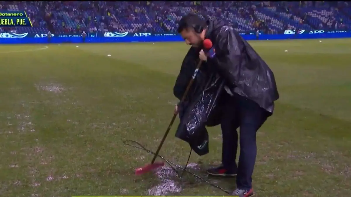 Reportero ayuda a sacar agua de la cancha tras suspensión del Puebla vs Chivas
