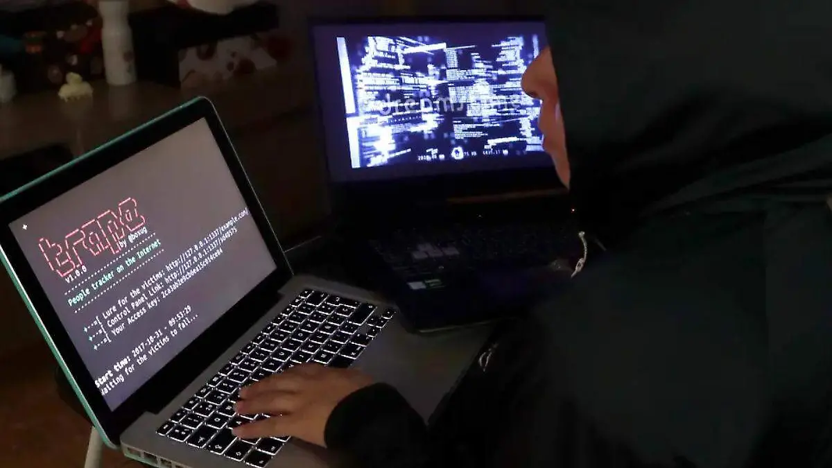 ciberdelincuentes, hackers, persona frente a dos computadoras