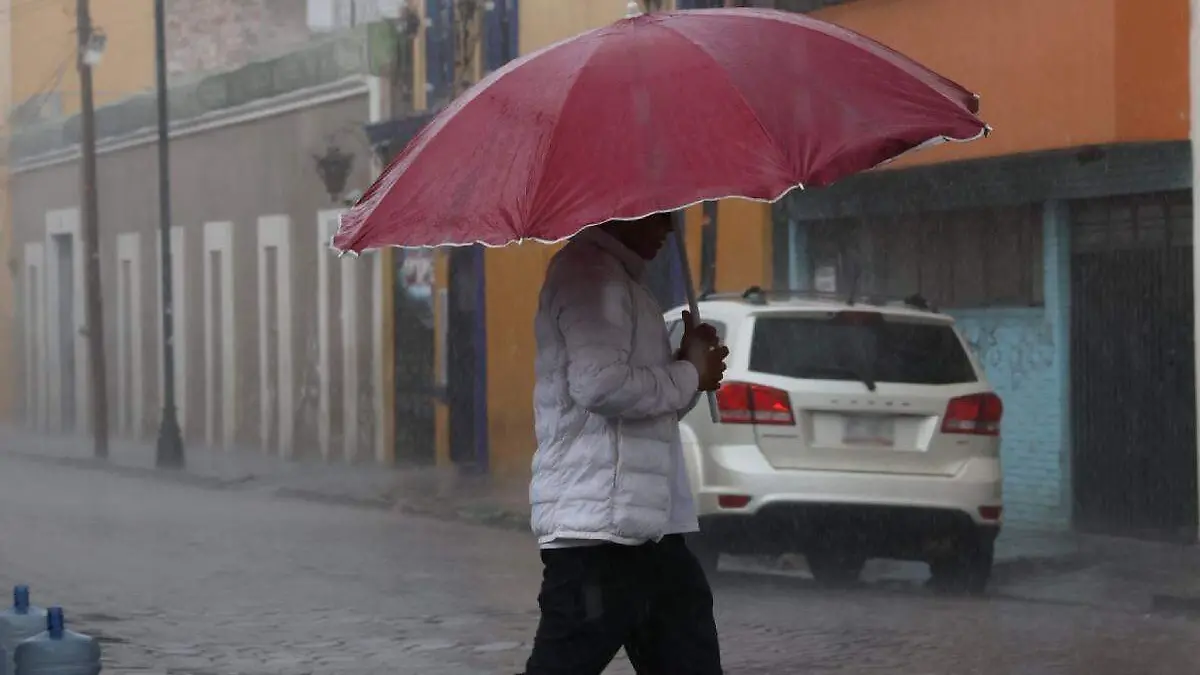 lluvia sobre la ciudad, persona camina con su paraguas bajo la lluvia