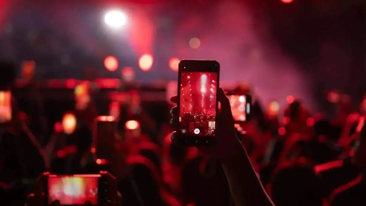 persona toma fotografia con un celular durante un concierto