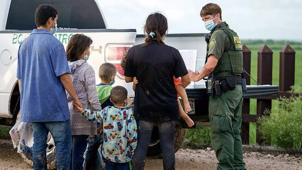 Agente de la patrulla fronteriza de EU con migrantes para transportarlos a bordo de una camioneta patrulla