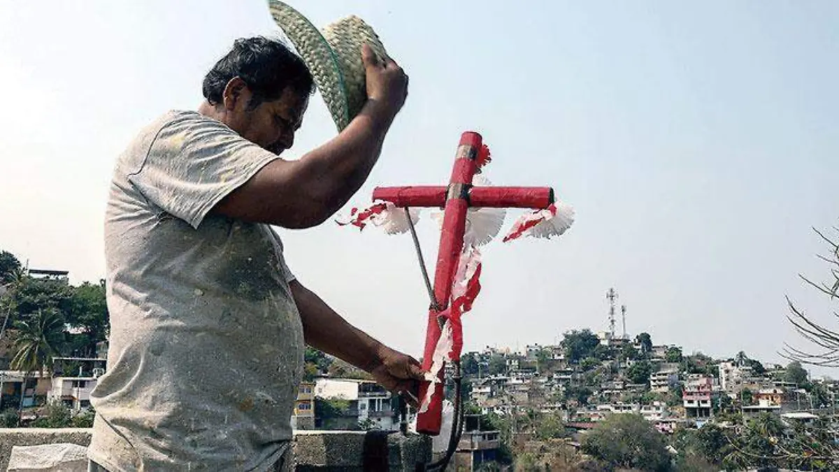 Albañilcolocandounacruzreverenciándola