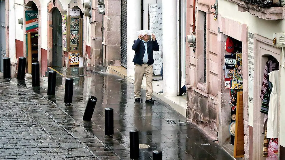 Hombre se cubre de la lluvia en tanto camina por el centro de Zacatecas