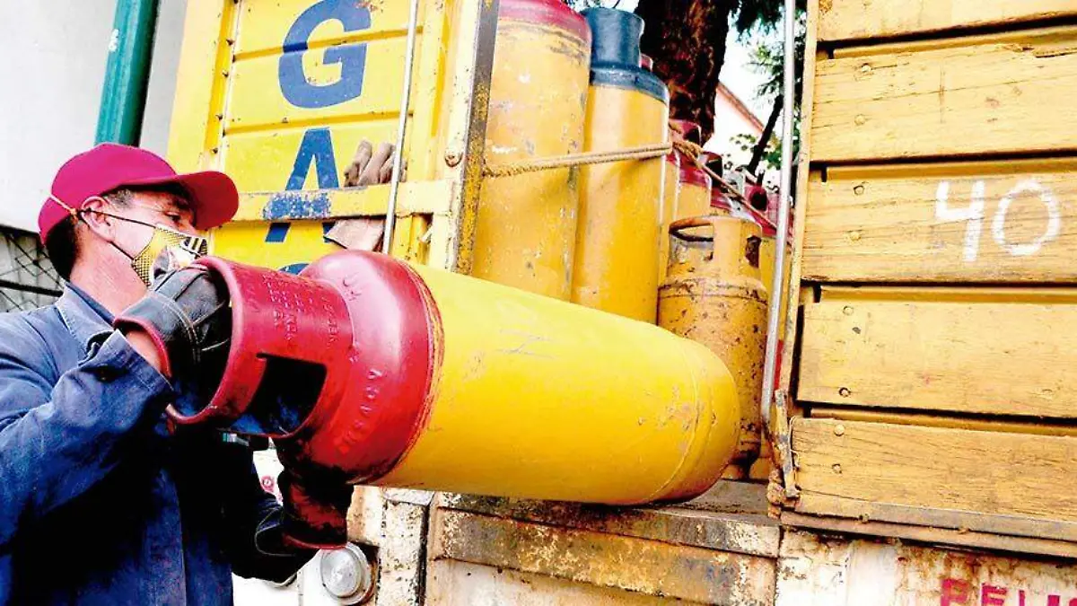 Un repartidor de tanques de gas sube al camión un cilindro vacío