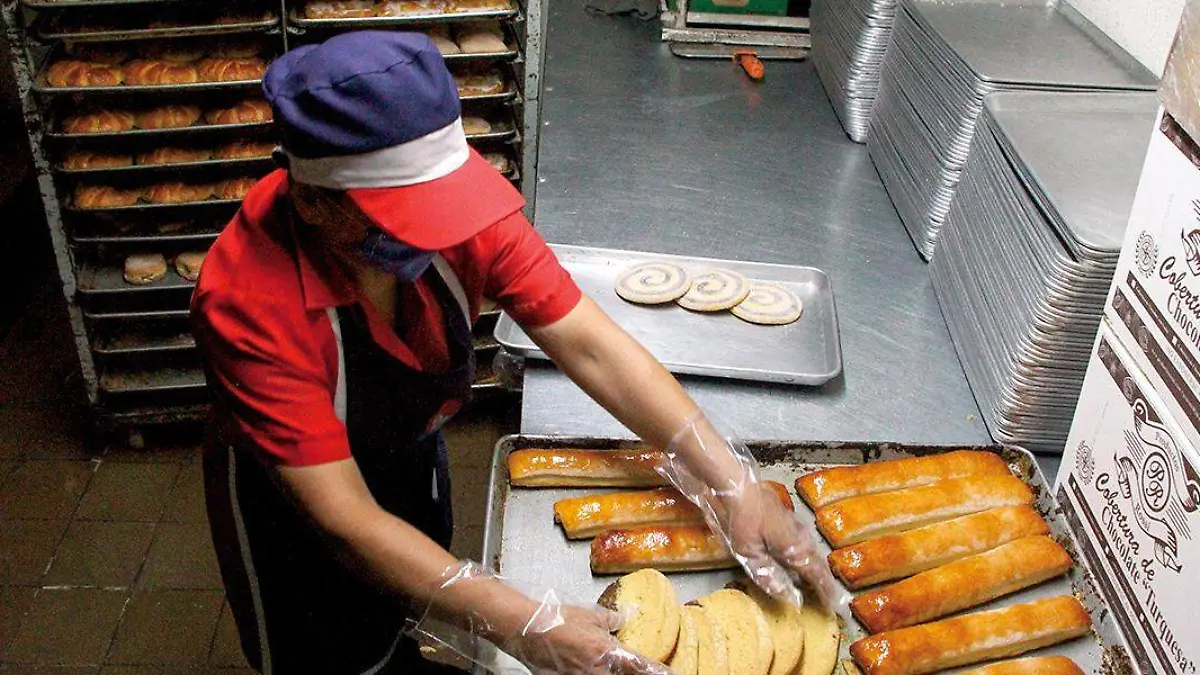 Trabajadora de panadería acomoda el pan en una charola