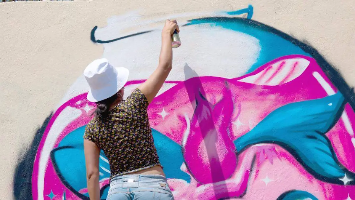 Mujer realizando mural de graffiti