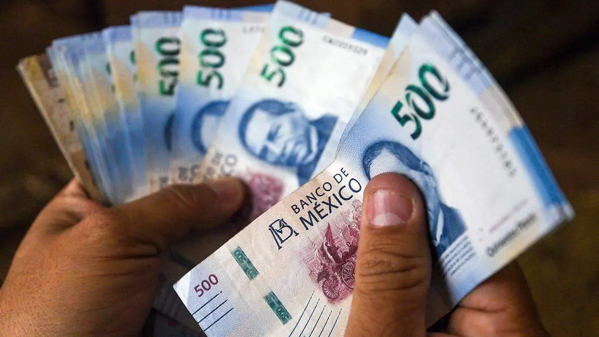 Manos con billetes mexicanos