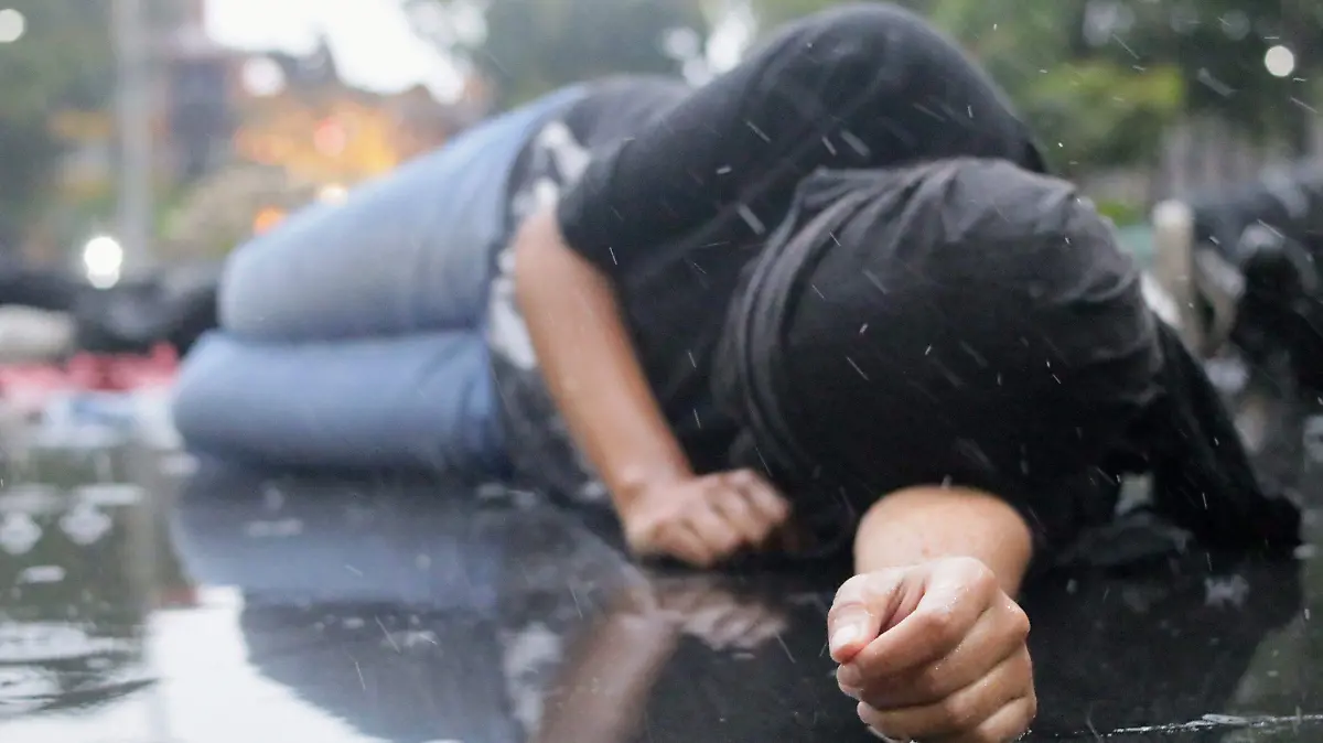 Joven sobre una banqueta bajo la lluvia