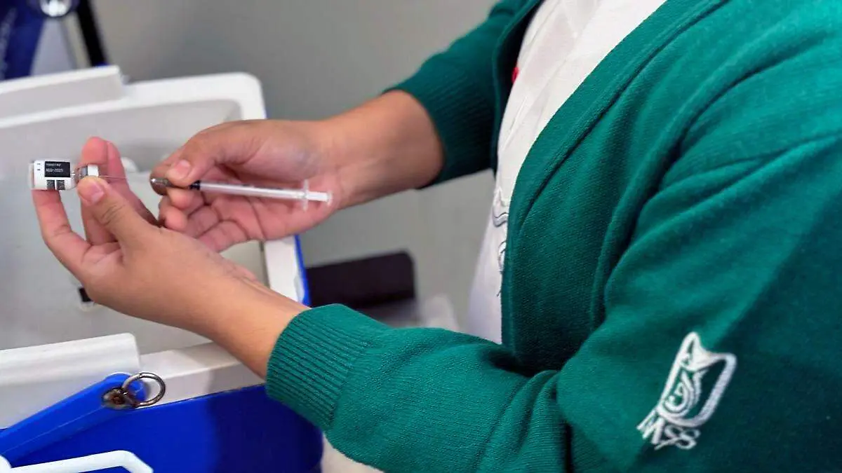 Enfermera IMSS preparando vacuna contra sarampión