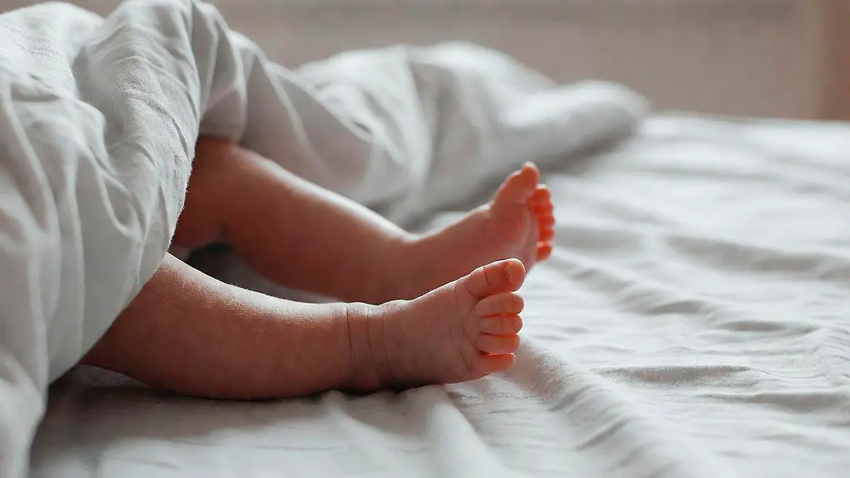 Imagen ilustrativa pies de bebé sobre una cama