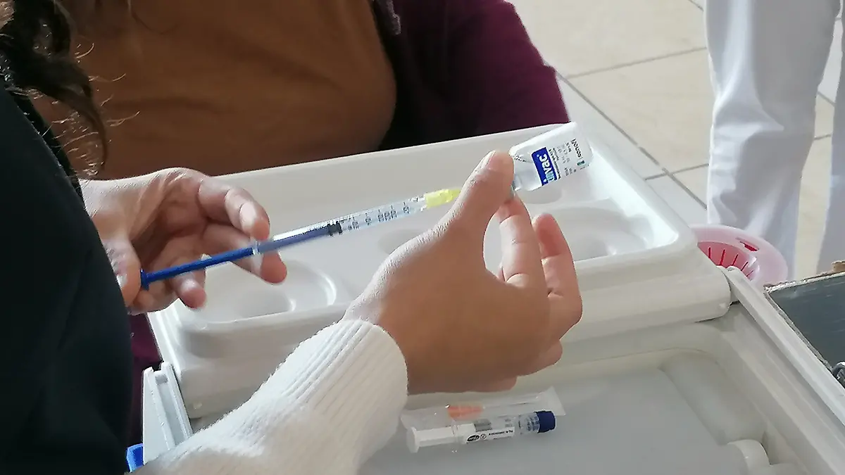 Enfermera prepara jeringa con vacuna contra influenza