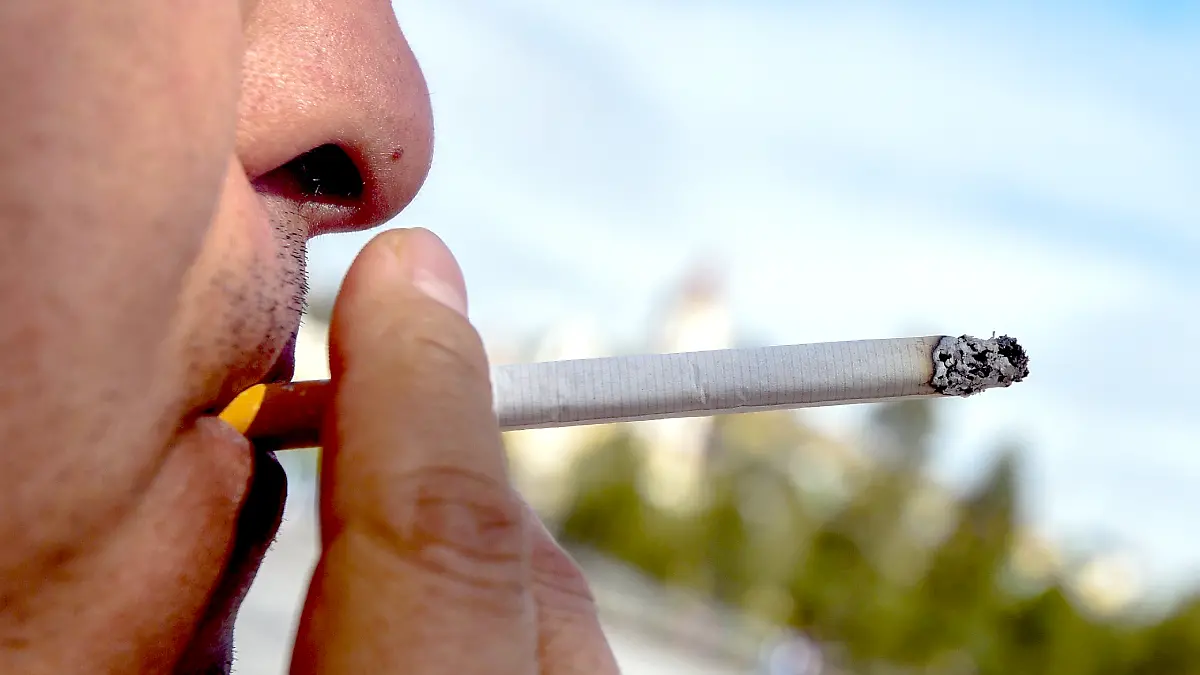 Hombre fumando en la vía pública