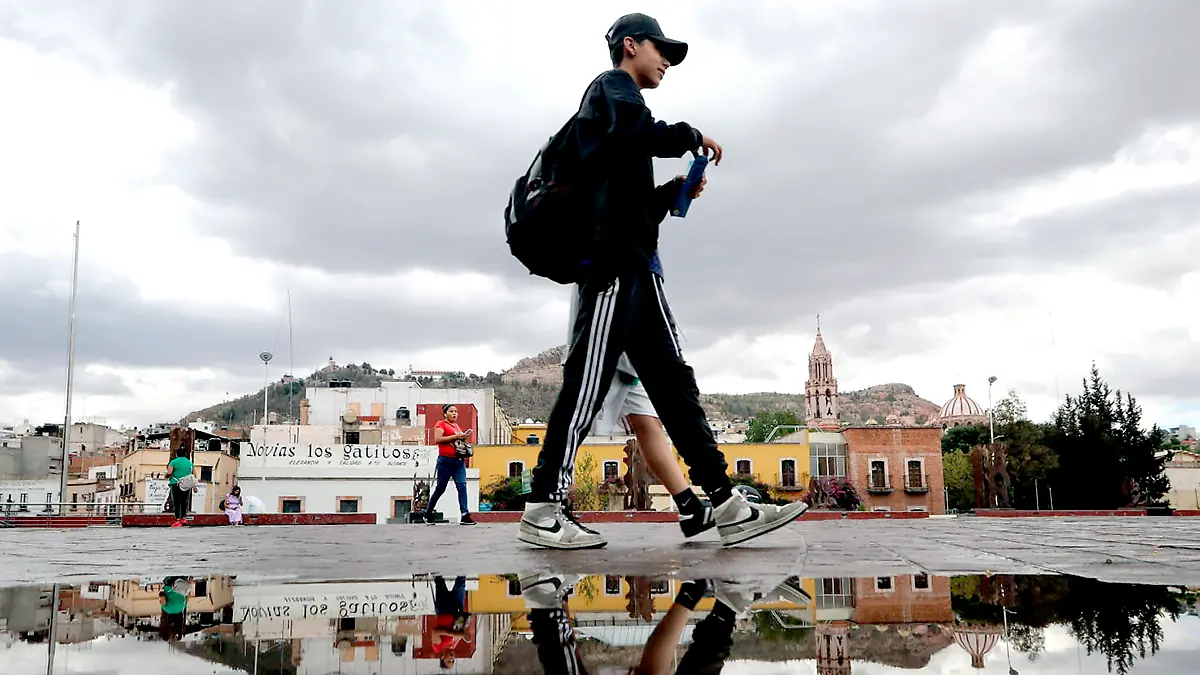 Joven camina por una plaza en Zacatecas en una tarde lluviosa