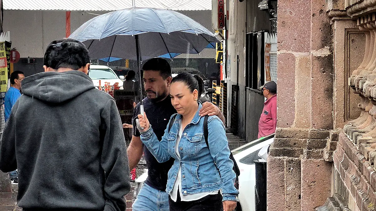 Personas caminan bajo la lluvia cubriéndose con una sombrilla en Zacatecas