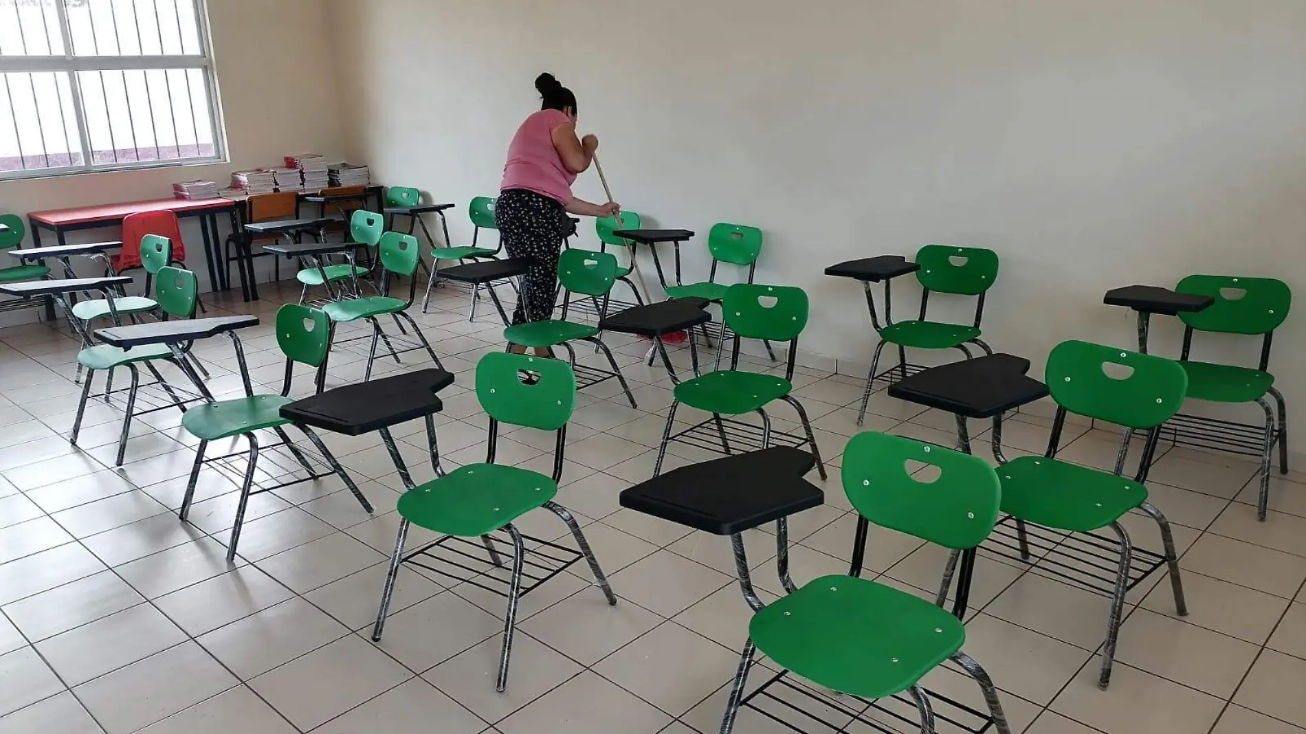 Mujer barre aula de escuela primaria