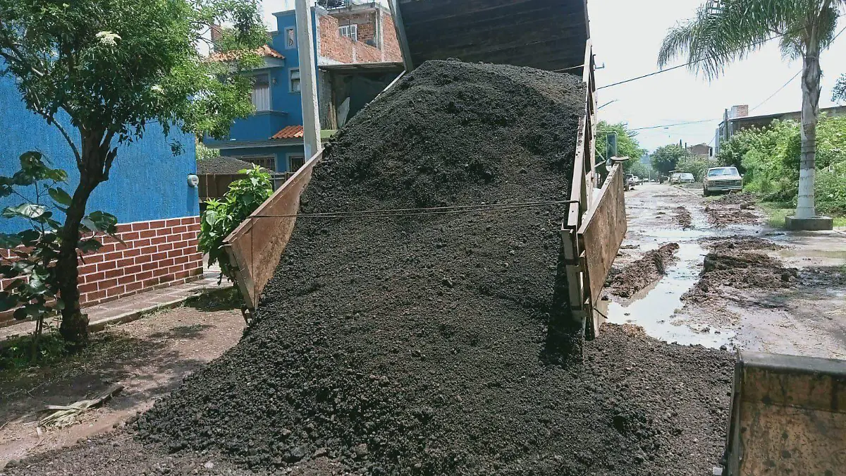 Camión vierte material para rehabilitar calle