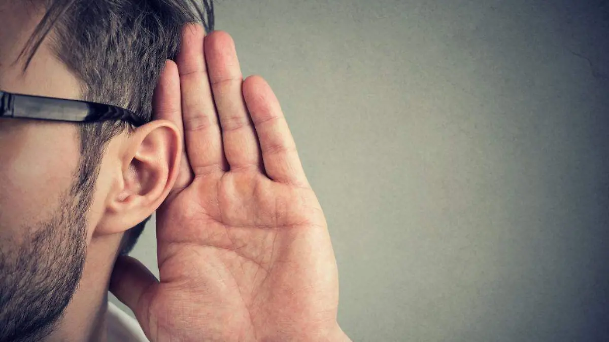 Persona levanta la oreja para esuchar