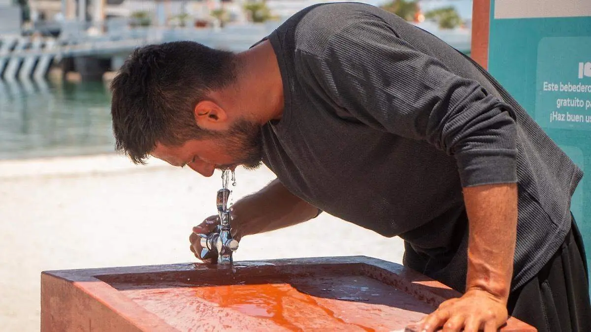 Persona bebiendo agua en el malecon de la paz por el calor