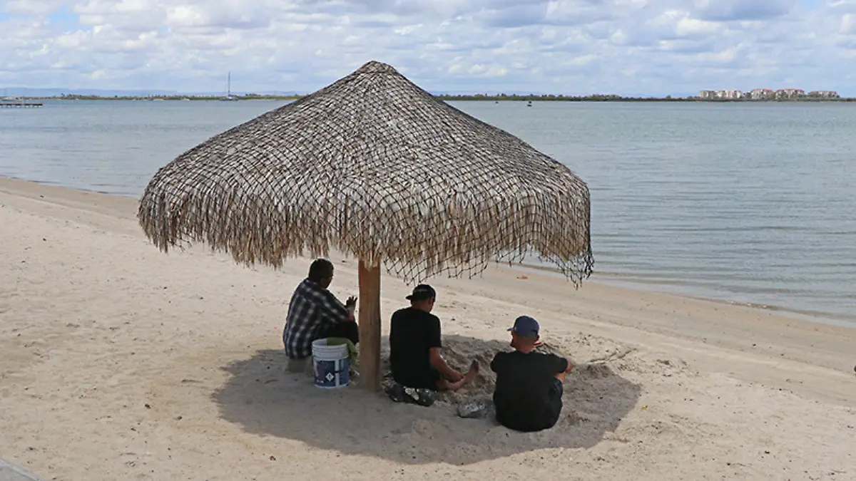personas-bajo-palapa-playa-malecon-la-paz